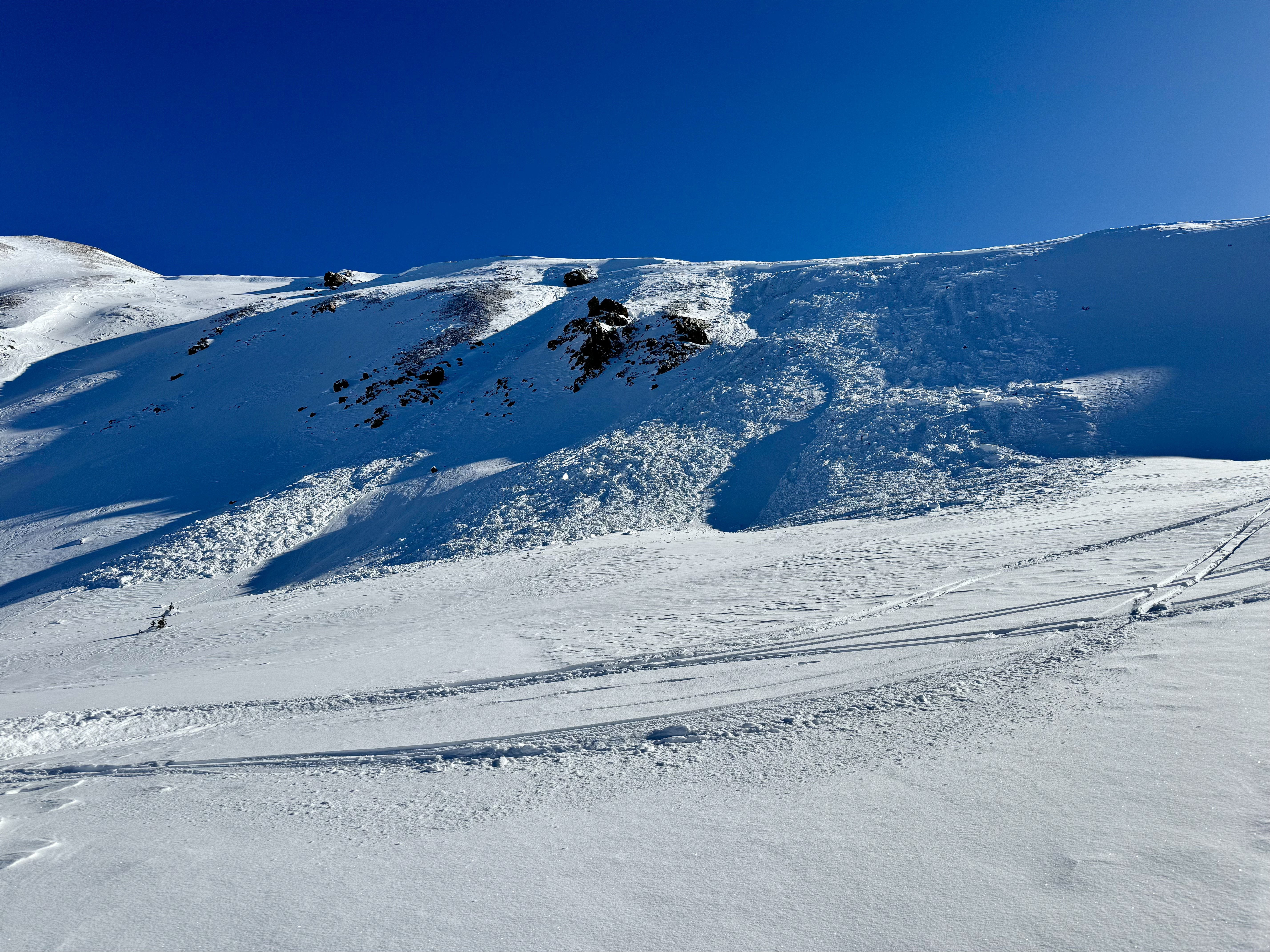 Looking straight ahead at a large avalanche on a shadowy slope 