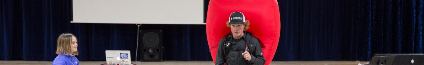Looking over children sitting at a CAIC forecaster demonstrating using an airbag 