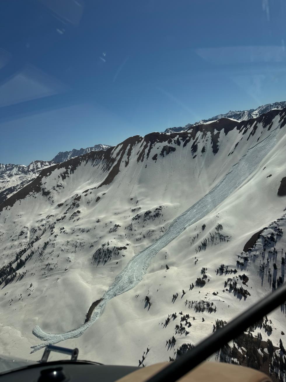 A mountain with a large Wet Slab avalanche and a clear blue sky.