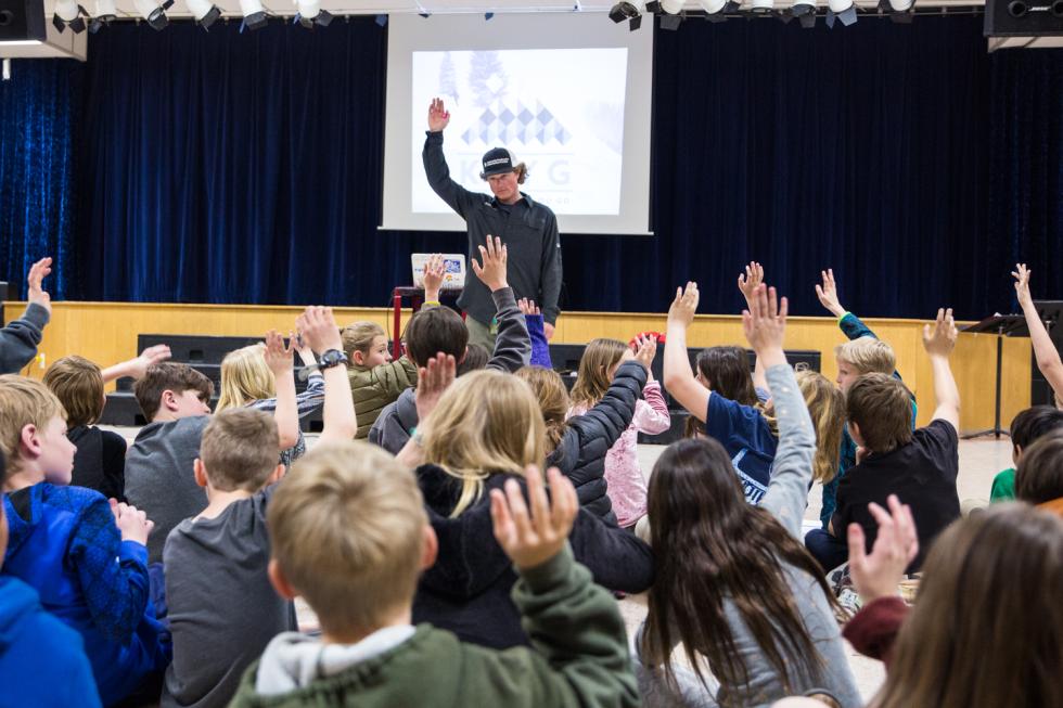 Looking at the back of kids' raising their hands with a forecaster in the front presenting to them