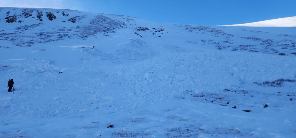 A person standing with a backpack amidst avalanche debris.